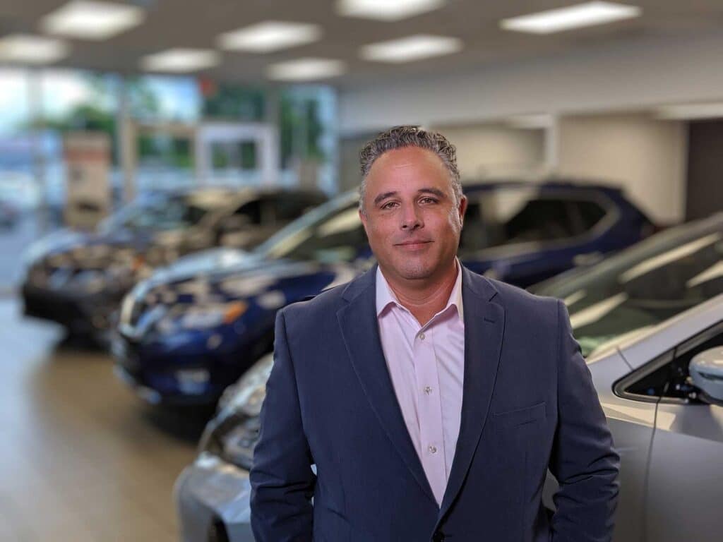 A man in a suit photographed inside an automotive showroom