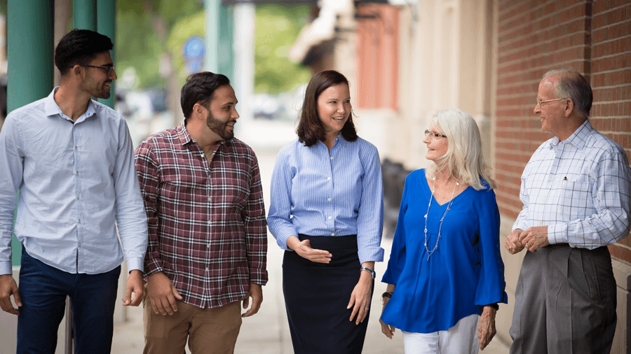 A group walking and talking together along a neighborhood sidewalk