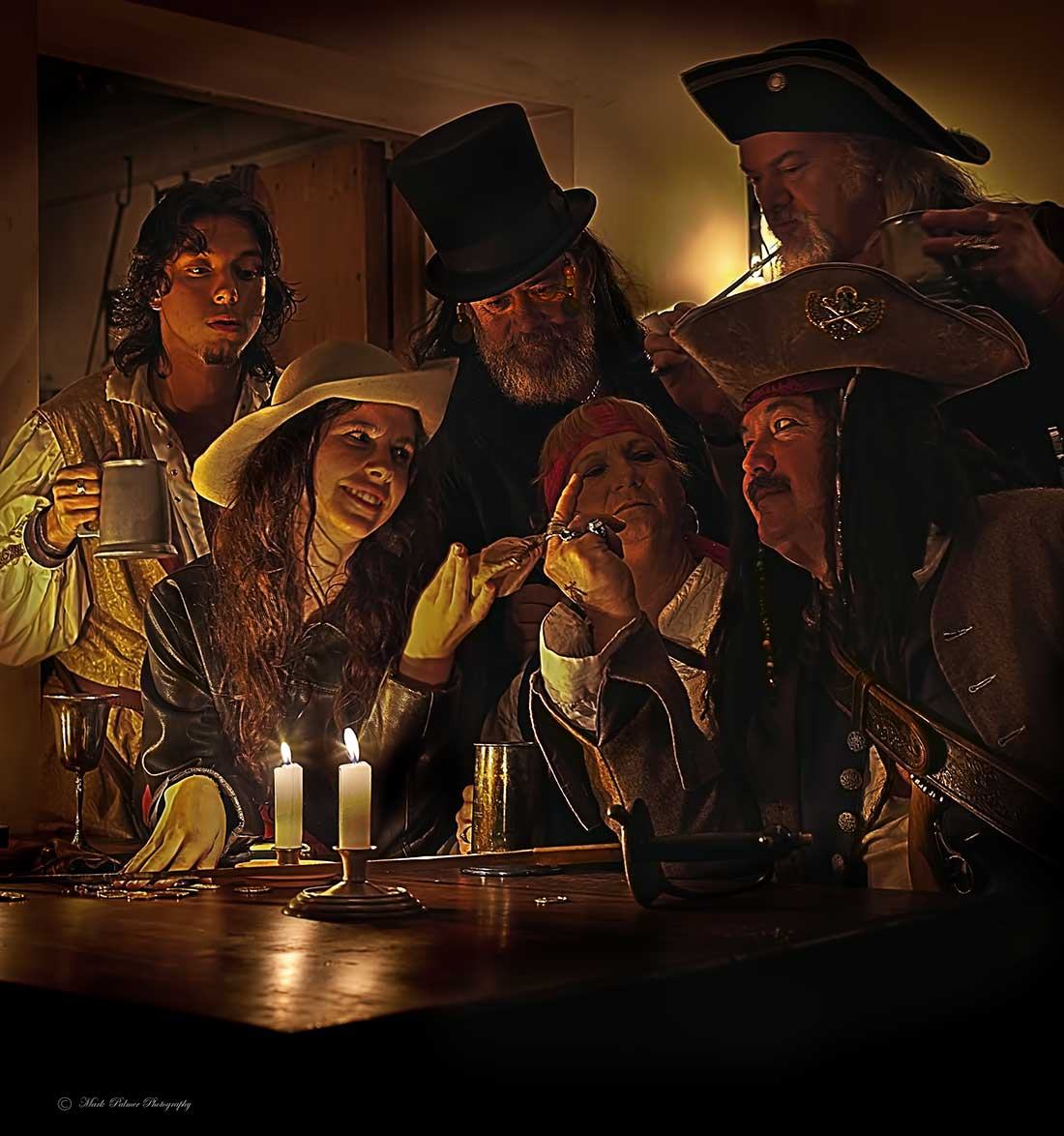 Costumed pirates gathered around a candlelit table